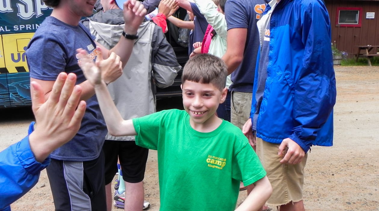 camper high fiving others while arriving at camp