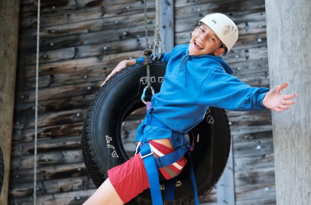 boy hanging onto a tire swing