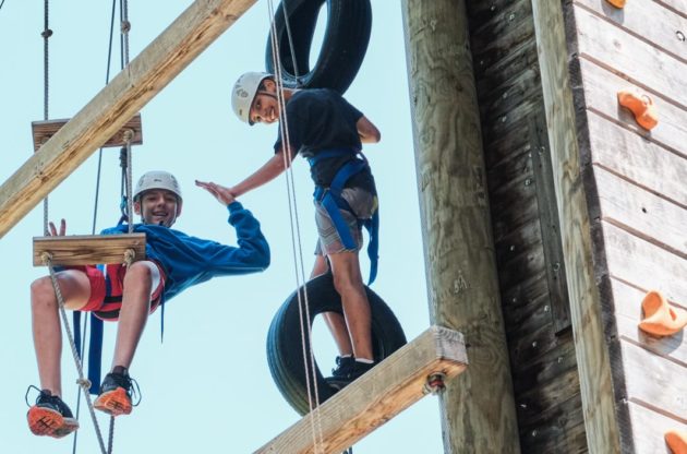 two campers on ropes course high fiving