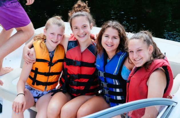 four girls in life jackets on a boat