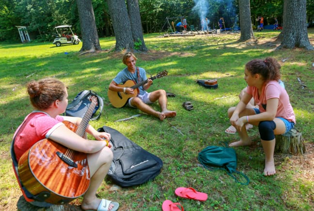 campers outside playing guitar