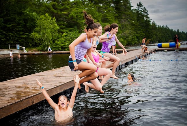 campers jumping off dock into lake