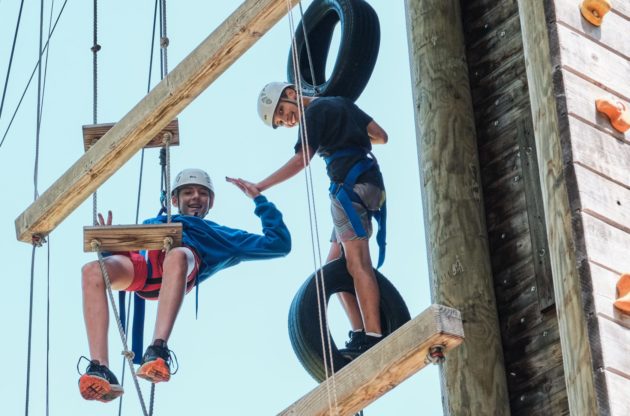 two campers on ropes course high fiving