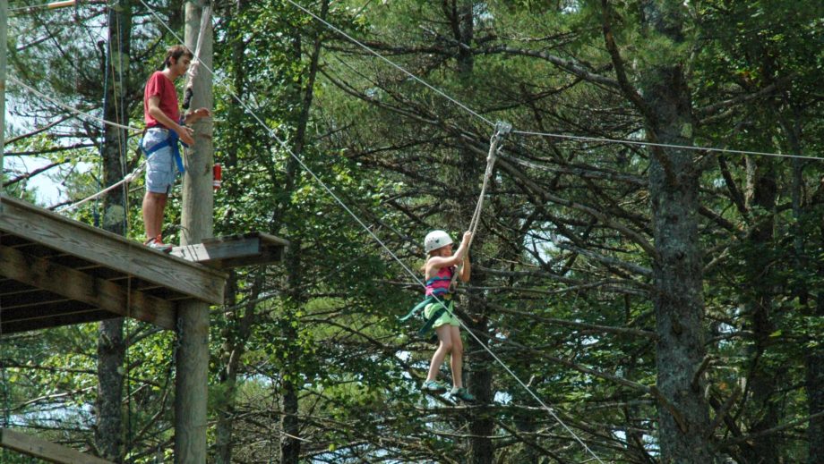 girl ziplining through trees